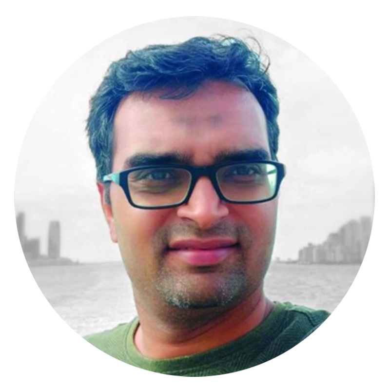 Man with glasses smiling, city skyline in background.